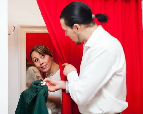 Couple trying coat in fitting-room — Stock Photo, Image