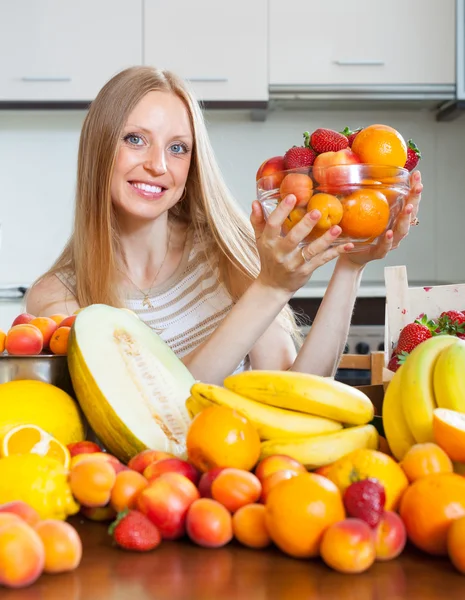 Mujer feliz con montón de frutas diversas — Foto de Stock