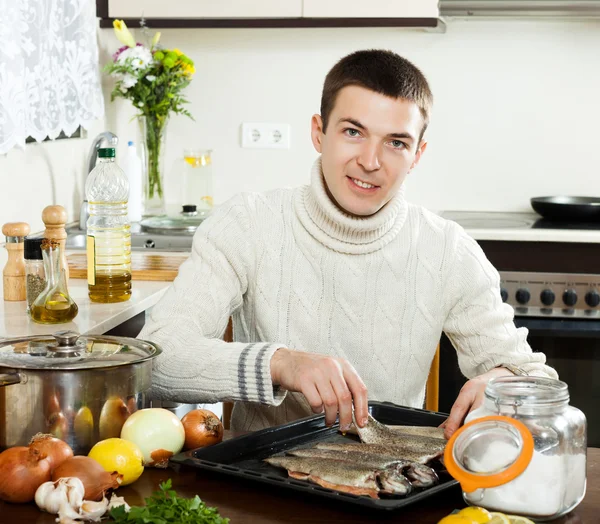 Uomo sorridente mettere pesce di acqua salata in tegame foglio — Foto Stock