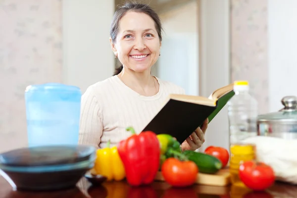 Mujer cocinando con libro de cocina en la cocina en casa — Foto de Stock