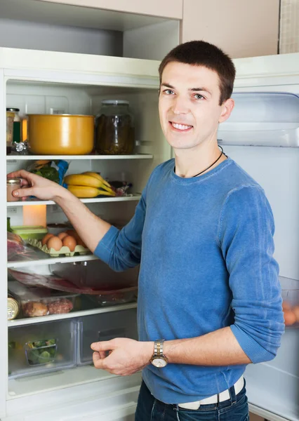Красивый парень возле открытого холодильника — стоковое фото