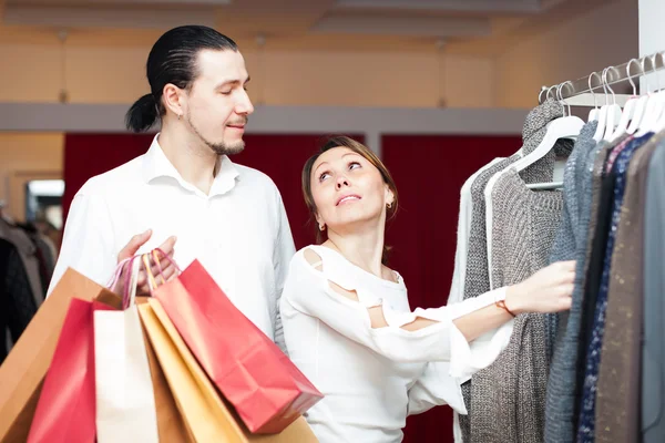 Couple with shopping bags choosing sweater — Stock Photo, Image