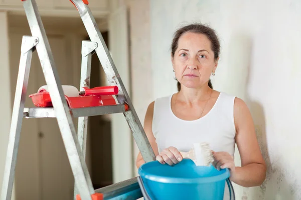 Mulher pinta parede com escova em casa — Fotografia de Stock