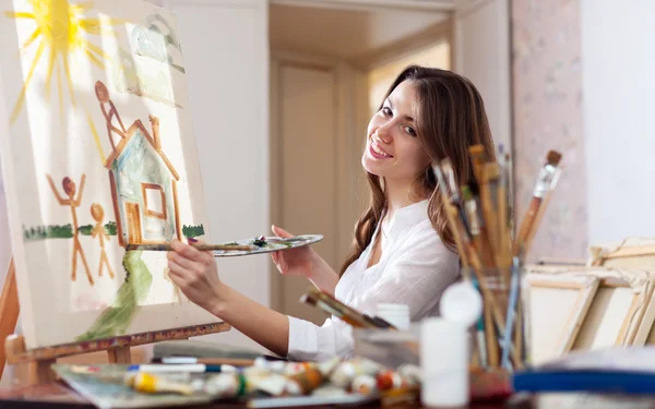 Счастливая женщина рисует дом мечты на холсте — стоковое фото