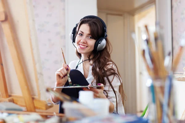 Female artist in headphones paints picture — Stock Photo, Image