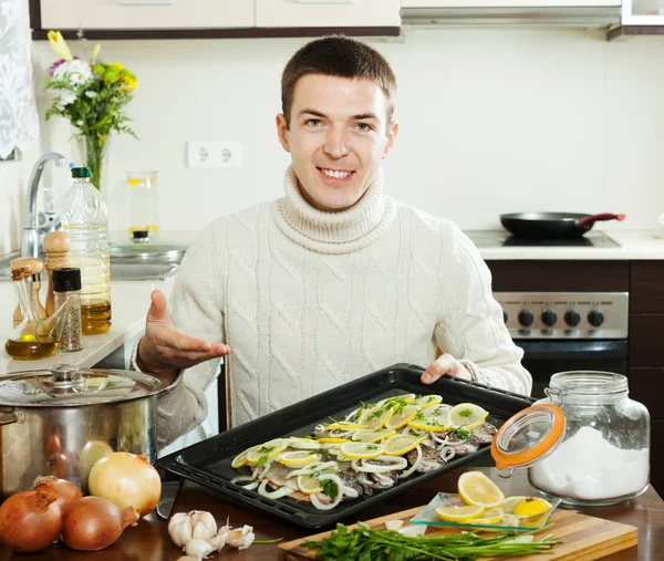 Glimlachende man koken vis met citroen in pan — Stockfoto