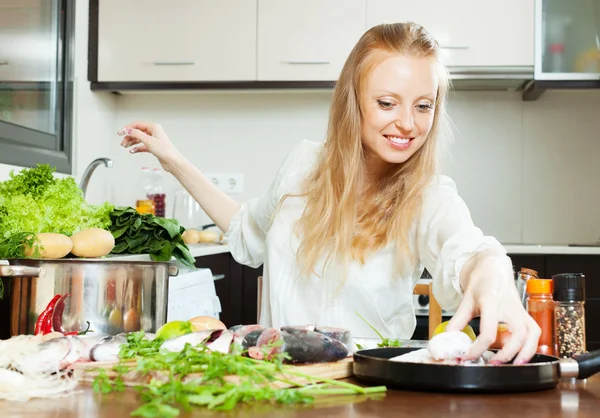 Happy woman putting  fish in flour into frying pan — Stock Photo, Image