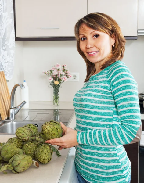 Mujer sonriente sosteniendo alcachofas — Foto de Stock