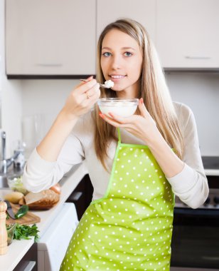 Smiling woman eating cottage cheese  clipart
