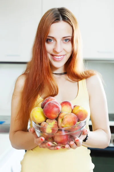 Glada houswife holding persikor — Stockfoto