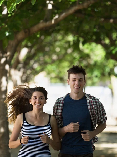 Sorrindo jovem casal correndo ao ar livre — Fotografia de Stock