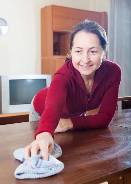 Volwassen vrouw schoonmaak houten tafel — Stockfoto