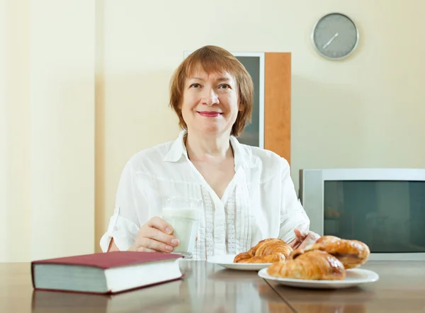 Mature woman having breakfast with milk — Stock Photo, Image