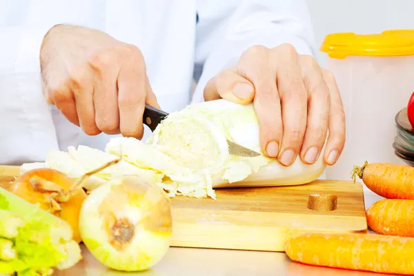 Mężczyzna gotuje warzywa z nożem — Zdjęcie stockowe