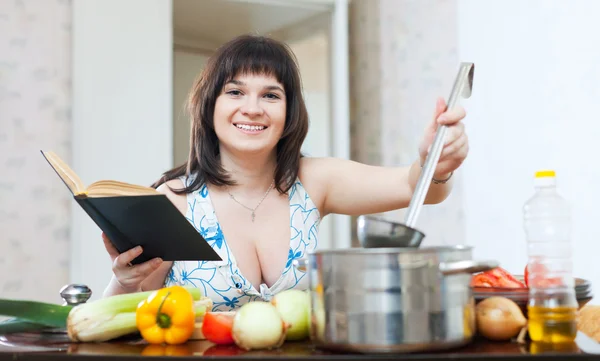 Femme cuisine avec livre de cuisine — Photo
