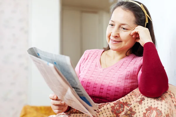 Mature woman reads newspaper — Stock Photo, Image