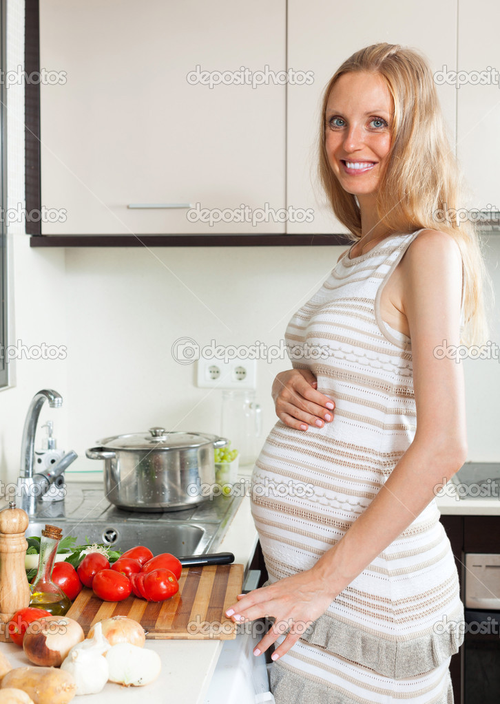 Pregnant girl cooking tomatoes Stock Photo by ©Jim_Filim 48986793