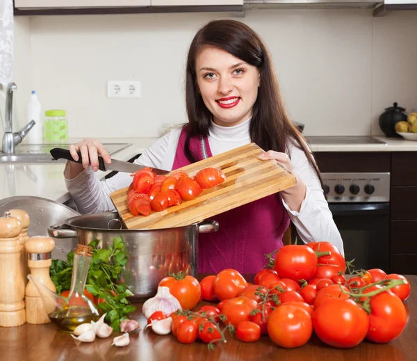 Усміхнена жінка готує з помідорами — стокове фото