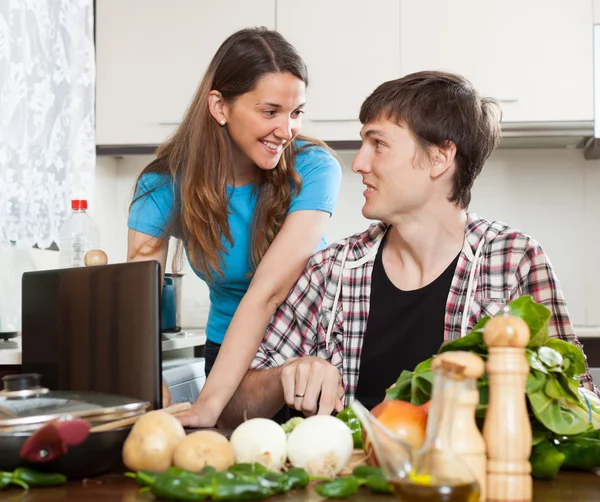 Couple looking at notebook during cooking — Stock Photo, Image