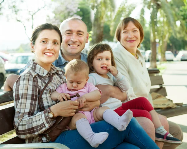 Familjen sitter på bänken — Stockfoto