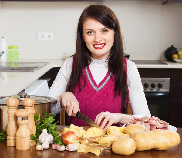 Kvinnan skära potatis på bordet — Stockfoto