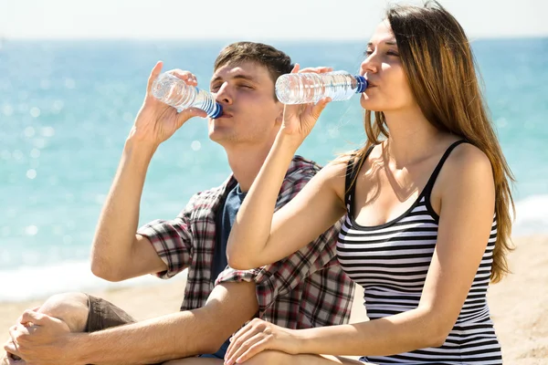 Paar am Strand trinkt Wasser — Stockfoto