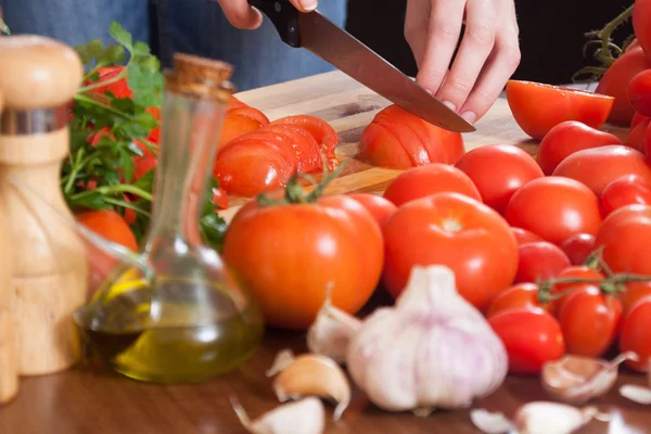 Vrouwelijke handen snijden tomaten — Stockfoto
