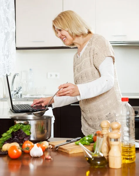 Mujer usando cuaderno mientras cocina —  Fotos de Stock