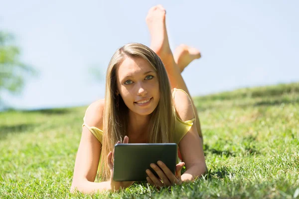 Ereader を読んで楽しんで草の上に横たわる少女 — ストック写真