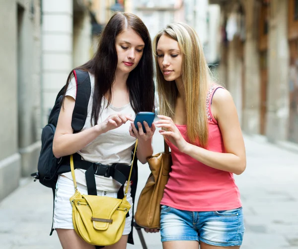 Twee vrouwelijke studenten met zakken met behulp van de kaart — Stockfoto