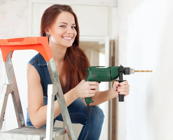 Mujer feliz taladra agujero en la pared — Foto de Stock