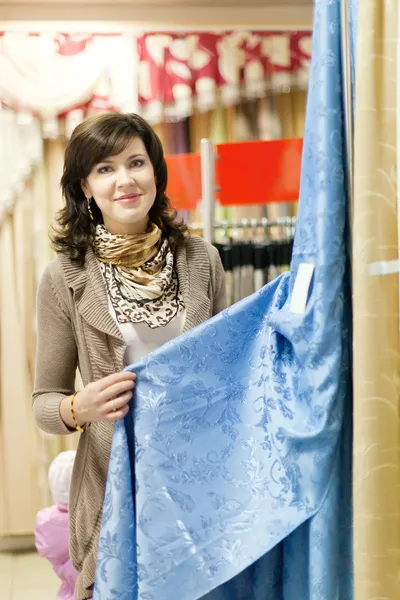 Mulher escolhe as cortinas — Fotografia de Stock