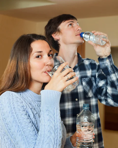 Pareja joven en su casa bebiendo agua — Foto de Stock