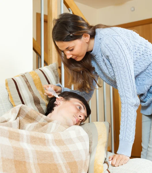 Chica goteando gotas para los oídos al hombre — Foto de Stock