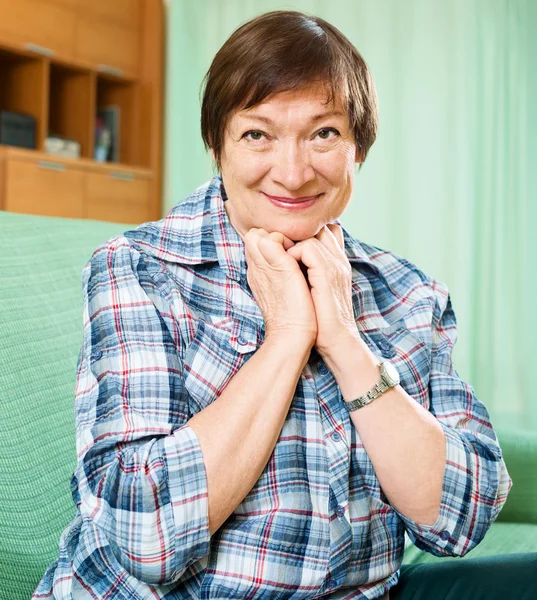 Reife Frau in lässiger Kleidung sitzt auf der Couch — Stockfoto