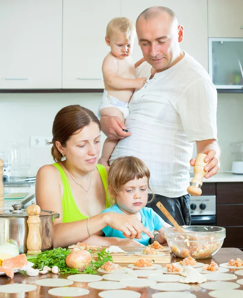 Family of four making dumplings with red fish — Stock Photo, Image