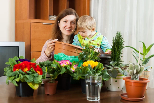 Madre con un niño pequeño trasplantando flores en maceta —  Fotos de Stock