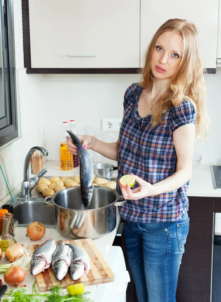 Flicka med rå fisk i köket — Stockfoto