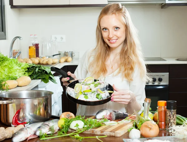 Smiling girl cooking fish  in frying pan — Stock Photo, Image