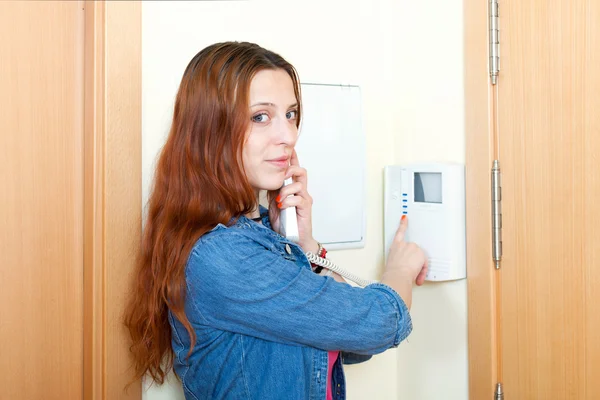 Rothaariges lächelndes Mädchen, das am Videotelefon des Hauses spricht — Stockfoto