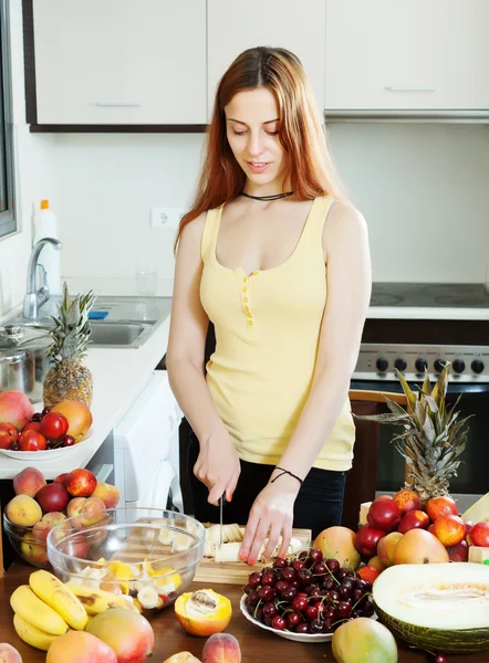 Mulher de cabelos longos positivo cozinhar salada de frutas — Fotografia de Stock