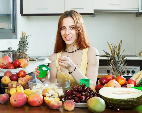 Positiv kvinna att göra fruktsallad med yoghurt — Stockfoto