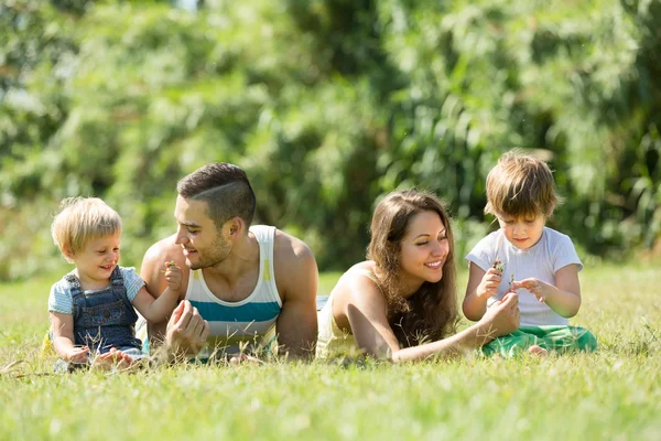 Eltern mit Kindern liegen im Gras — Stockfoto