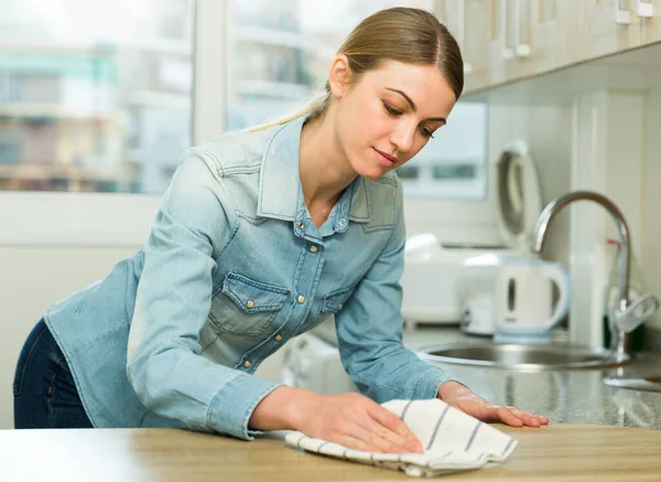 Smiling woman is cleaning surface on the kitchen at the home — Stock Photo, Image