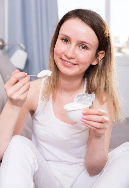 Jonge vrouw zit met yoghurt op de bank — Stockfoto