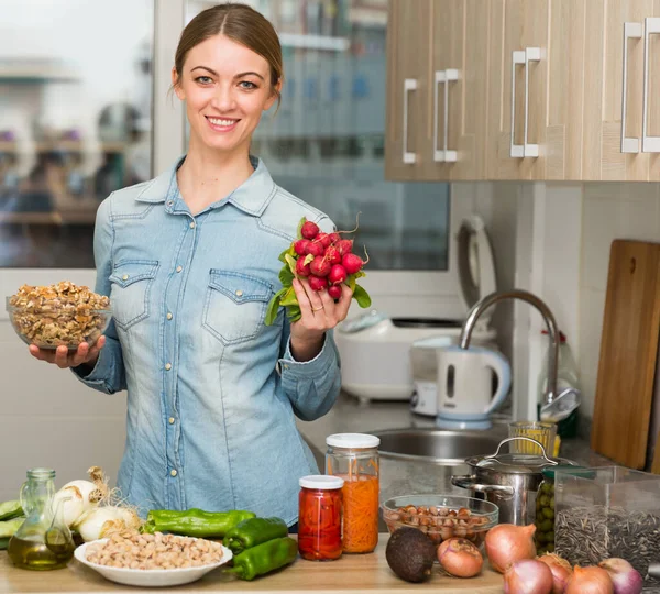 Mulher com produtos alimentares Positivo jovem mulher se preparando em casa cozinha — Fotografia de Stock