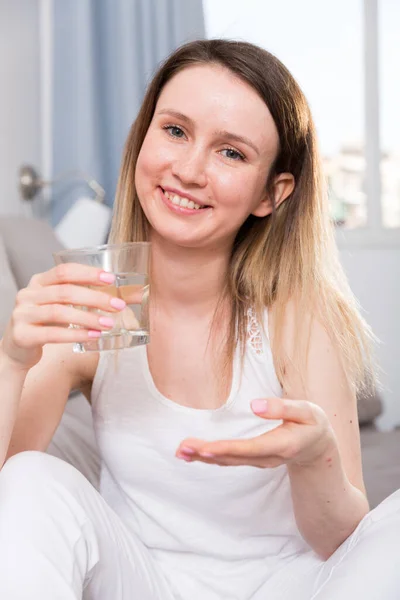 Junge Frau sitzt mit Wasser auf Sofa — Stockfoto