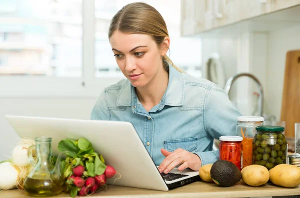 Mladá žena vaření recept z internetu — Stock fotografie