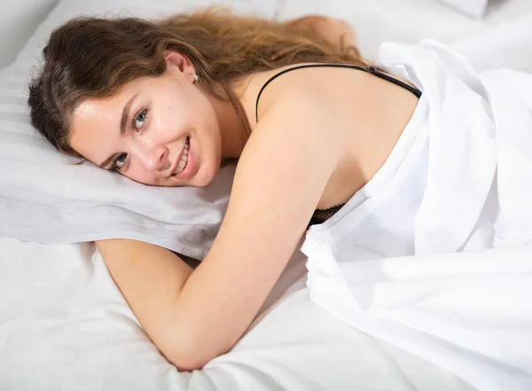 Ragazza coperta con lenzuolo bianco sdraiato a letto — Foto Stock