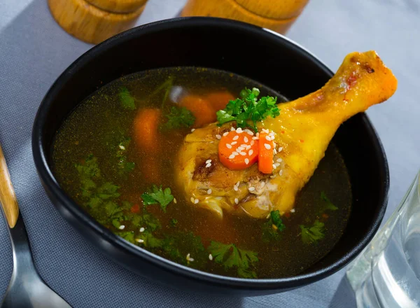 鶏足の細いスープをブラックボウルに入れる — ストック写真